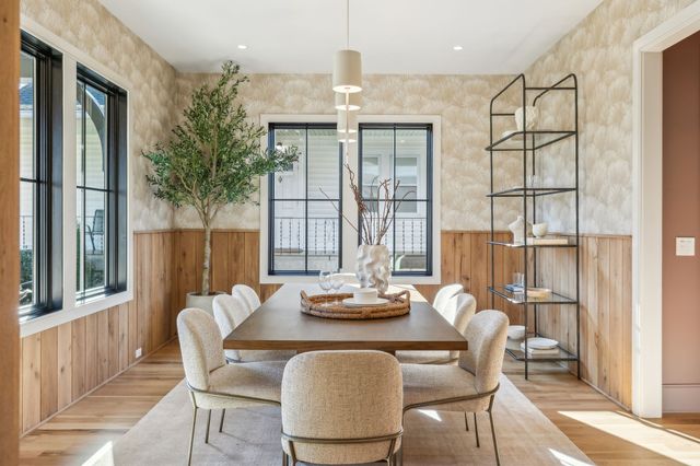 a kitchen with stainless steel appliances granite countertop a stove a refrigerator a sink a dining table and chairs with wooden floor