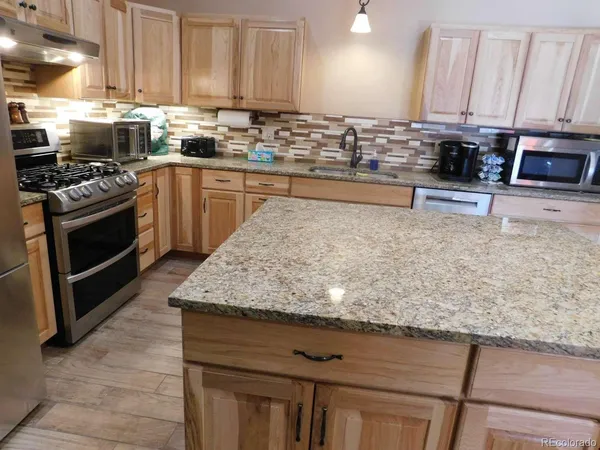 a kitchen with kitchen island granite countertop a sink a stove and cabinets