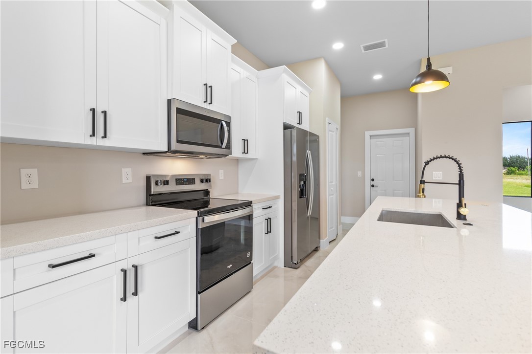 2809 25th Street Southwest Lehigh Acres, FL 33976 - Photo 11 of 36 a kitchen with stainless steel appliances a stove refrigerator a sink and a microwave