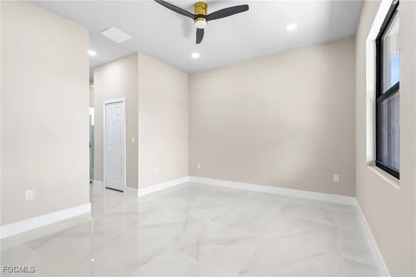 an empty room with ceiling fan and window