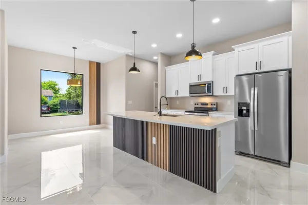 a kitchen with stainless steel appliances granite countertop a refrigerator a sink dishwasher a oven and a dining table with wooden floor