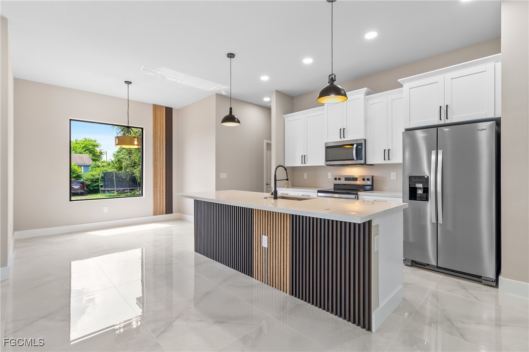 2809 25th Street Southwest Lehigh Acres, FL 33976 - Photo 6 of 36 a kitchen with stainless steel appliances granite countertop a refrigerator a sink dishwasher a oven and a dining table with wooden floor