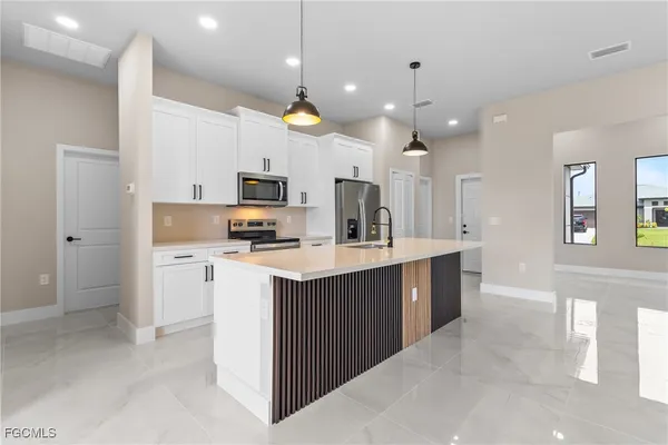 a kitchen with kitchen island a sink stainless steel appliances and cabinets