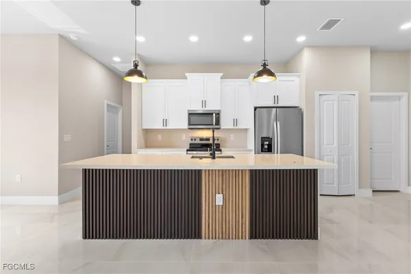 a kitchen with kitchen island a refrigerator a sink and a stove
