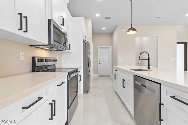 a large kitchen with stainless steel appliances kitchen island a large counter space a sink and cabinets