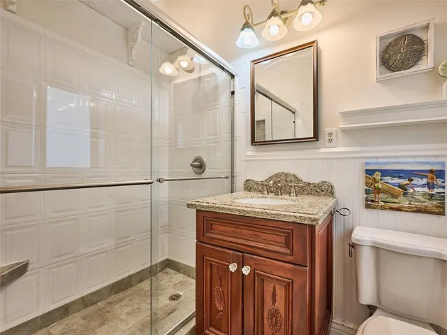 a bathroom with a granite countertop sink a toilet and shower