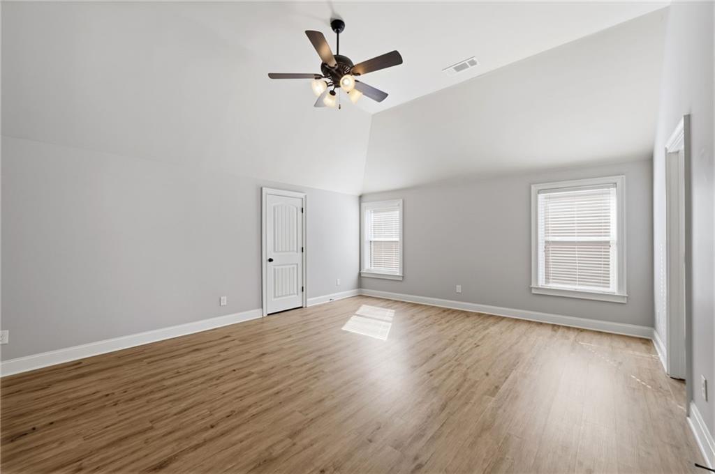 268 Clubhouse Crossing Acworth, GA 30101 - Photo 29 of 48 an empty room with wooden floor chandelier fan and windows