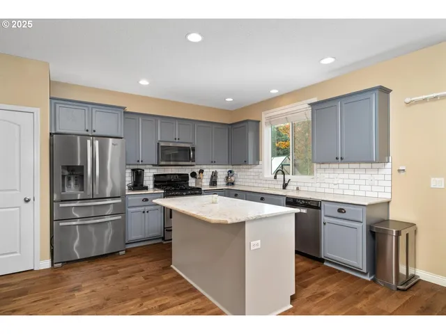 a kitchen with stainless steel appliances granite countertop a sink stove refrigerator and cabinets