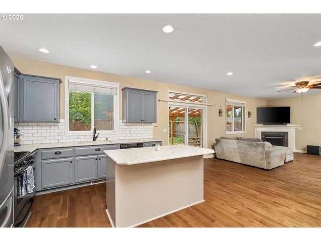 a large living room with stainless steel appliances granite countertop couches a flat screen tv and a refrigerator