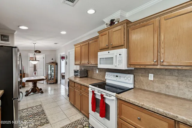 a large kitchen with a refrigerator a oven a sink a counter top space and cabinets