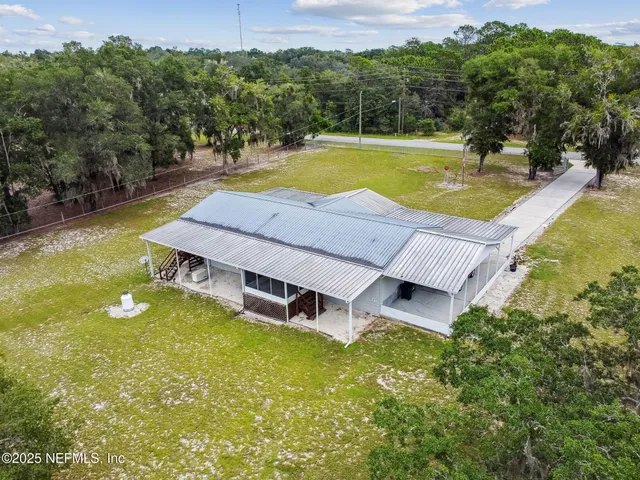 an aerial view of a house with swimming pool and large trees