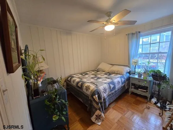 a bedroom with a bed table flowerpot and window