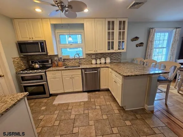 a kitchen with stainless steel appliances granite countertop a sink a stove a microwave a counter top space and cabinets