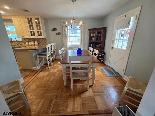 a living room with furniture a dining table wooden floor and a chandelier