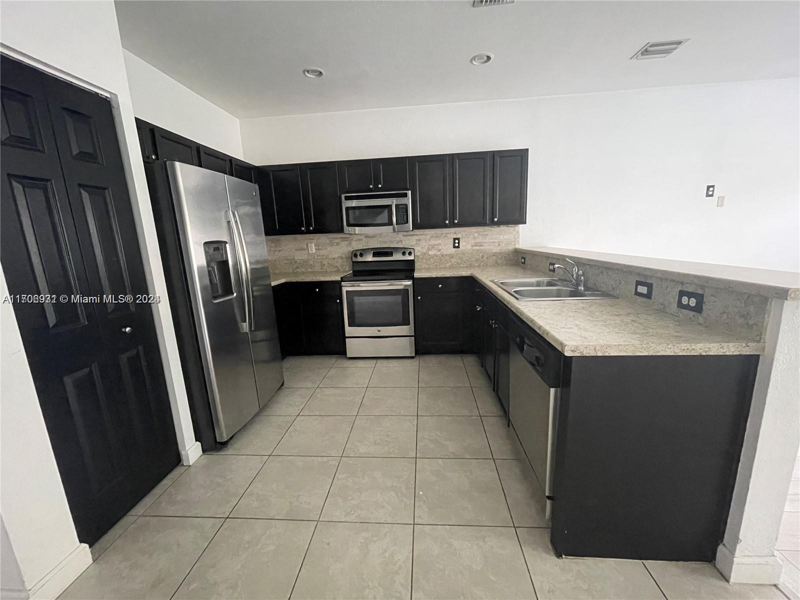 8905 West 35th Way Hialeah, FL 33018 - Photo 2 of 4 a kitchen with stainless steel appliances granite countertop a refrigerator a sink a stove top oven and a dishwasher