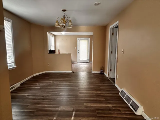 a view of an empty room with wooden floor and a chandelier