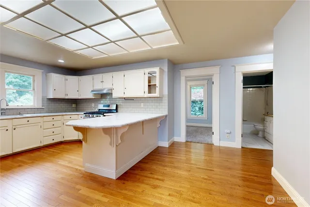 a kitchen with stainless steel appliances granite countertop a sink cabinets and wooden floor