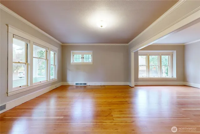 a view of an empty room with wooden floor and a window