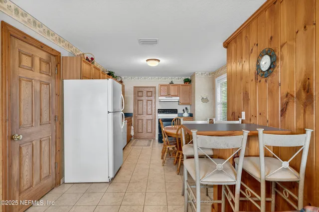a dining room filled a chandelier and kitchen view