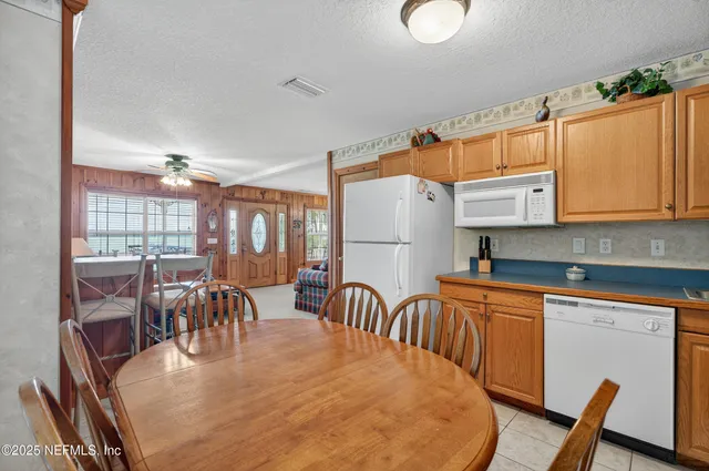 a kitchen with stainless steel appliances granite countertop a dining table chairs refrigerator and sink