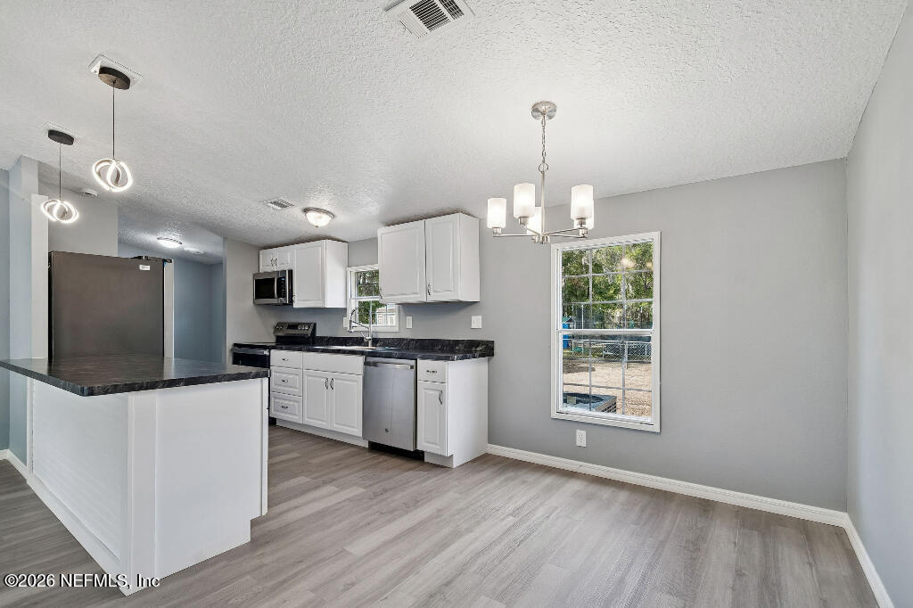 101 Ridgewood Avenue Interlachen, FL 32148 - Photo 7 of 25 a kitchen with stainless steel appliances granite countertop a stove a sink dishwasher a refrigerator and a fireplace with wooden floor