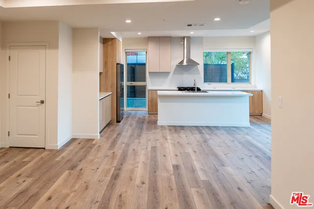 a large kitchen with stainless steel appliances a large counter top a refrigerator and a sink