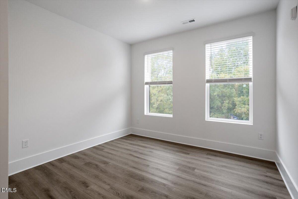 509 Kildaire Farm Road, Unit 302 Cary, NC 27511 - Photo 27 of 30 an empty room with wooden floor and windows
