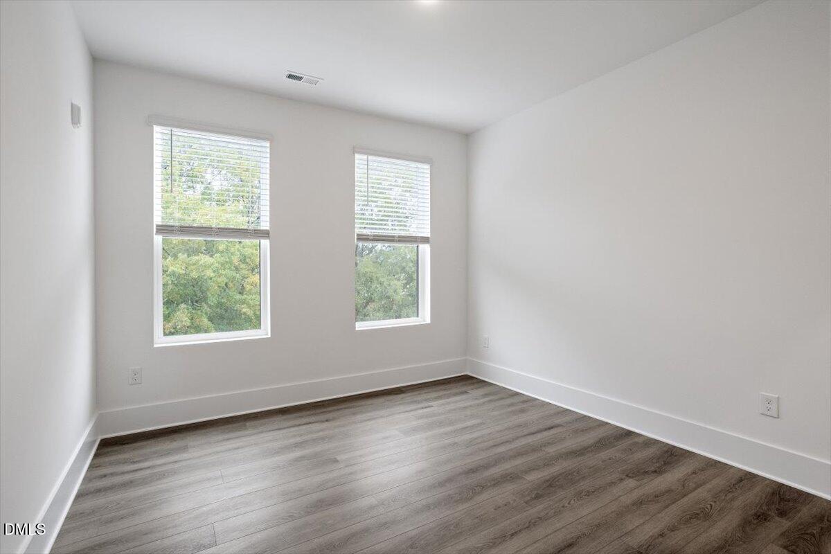 509 Kildaire Farm Road, Unit 302 Cary, NC 27511 - Photo 29 of 30 an empty room with wooden floor and windows