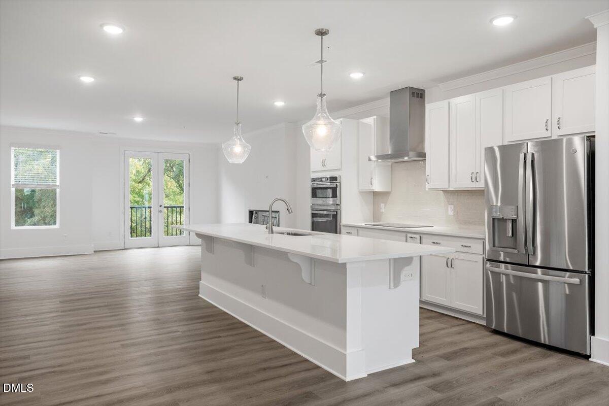 509 Kildaire Farm Road, Unit 302 Cary, NC 27511 - Photo 5 of 30 a kitchen with stainless steel appliances granite countertop a refrigerator a sink dishwasher a stove and white cabinets with wooden floor