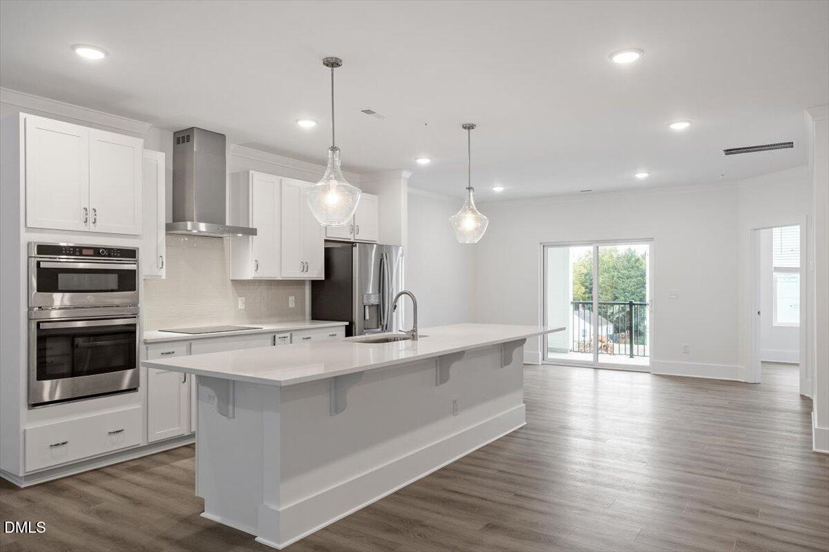 509 Kildaire Farm Road, Unit 302 Cary, NC 27511 - Photo 7 of 30 a large kitchen with kitchen island a large counter space a sink appliances and a window