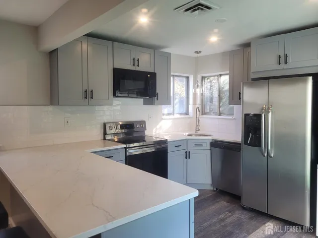 a kitchen with stainless steel appliances granite countertop a refrigerator a sink a stove a microwave and wooden cabinets