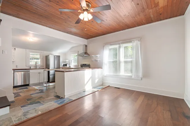 a view of empty room with wooden floor and kitchen view