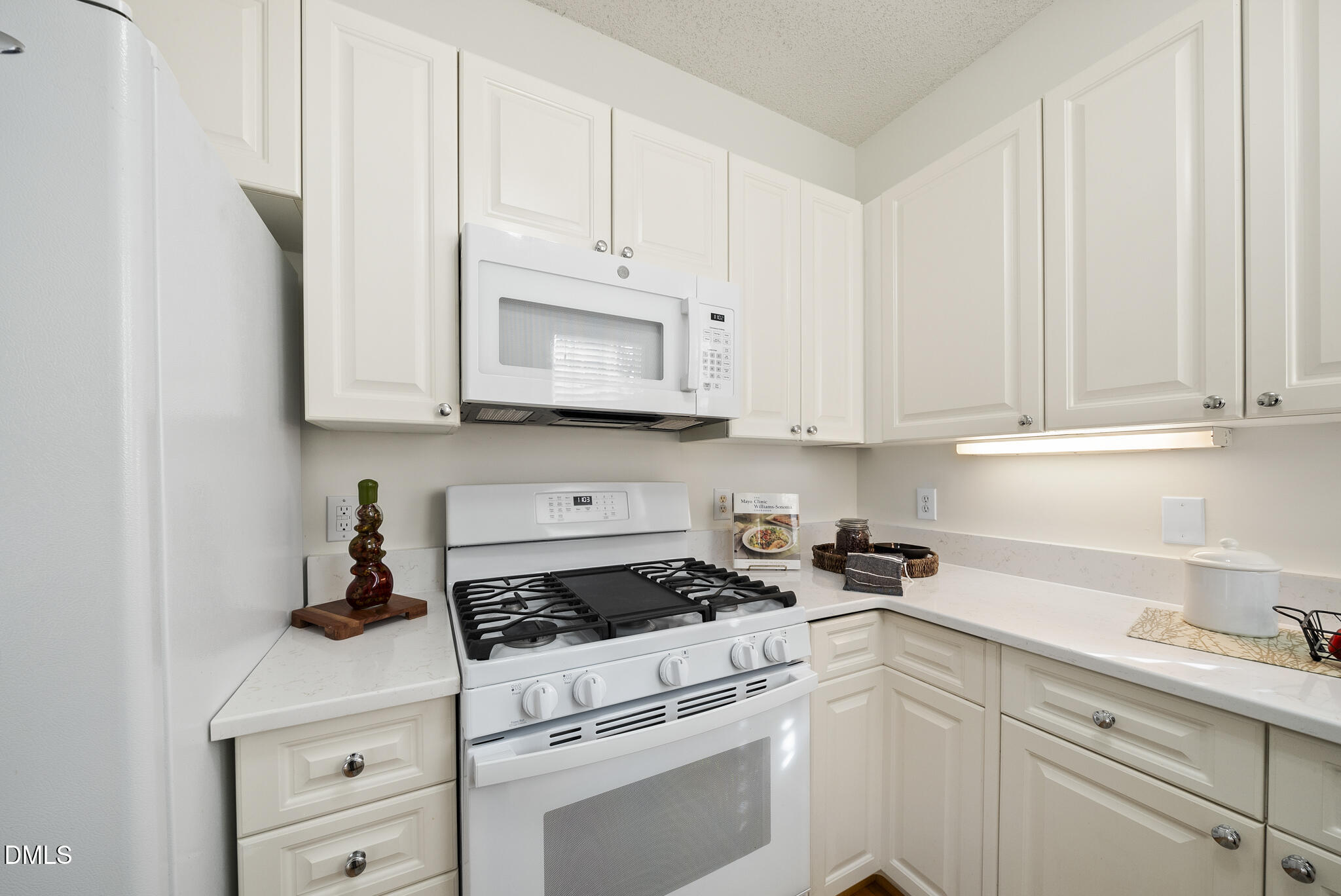 7710 Astoria Place Raleigh, NC 27612 - Photo 11 of 34 a kitchen with white cabinets and white appliances