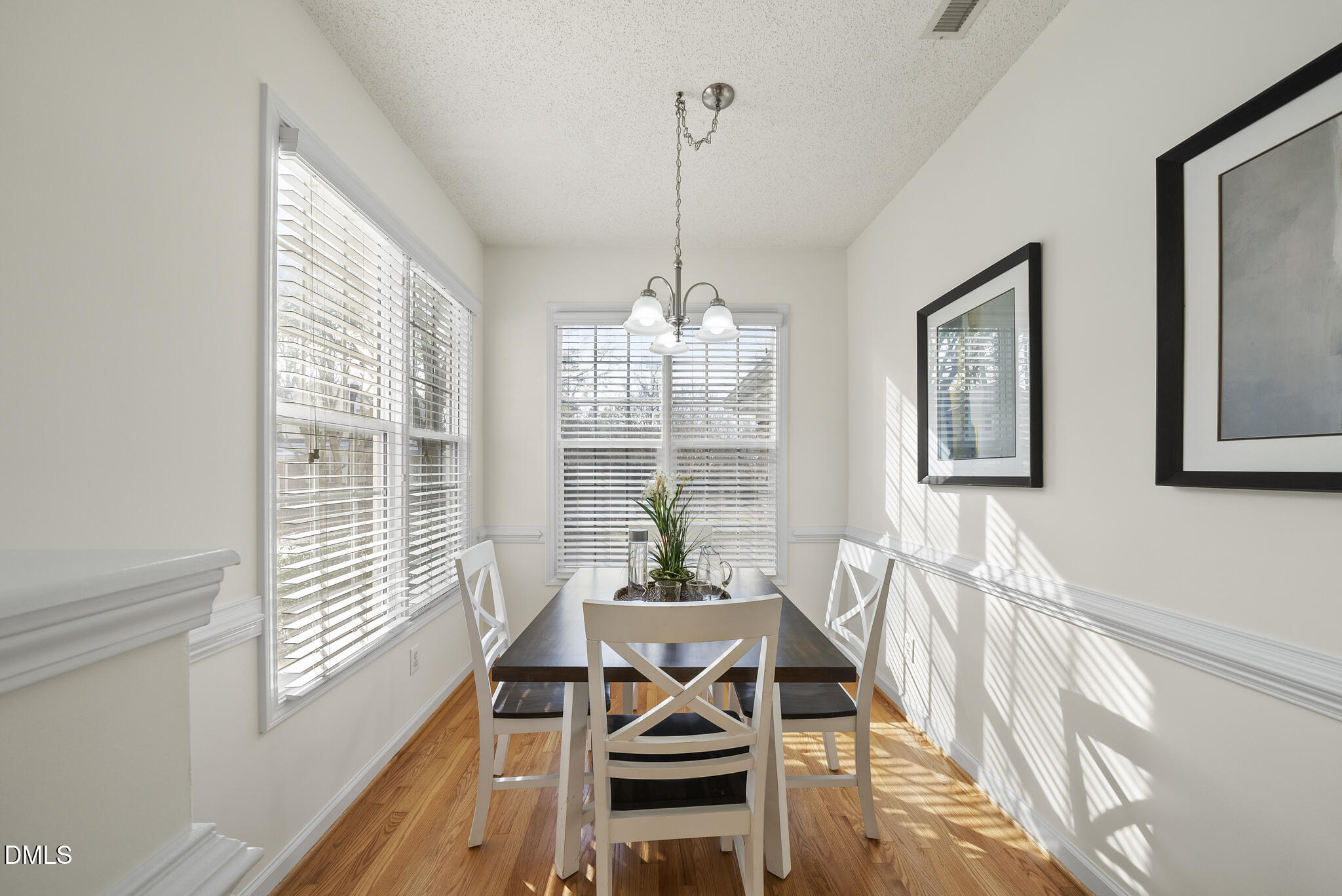 7710 Astoria Place Raleigh, NC 27612 - Photo 13 of 34 a view of a dining room with furniture wooden floor and a chandelier