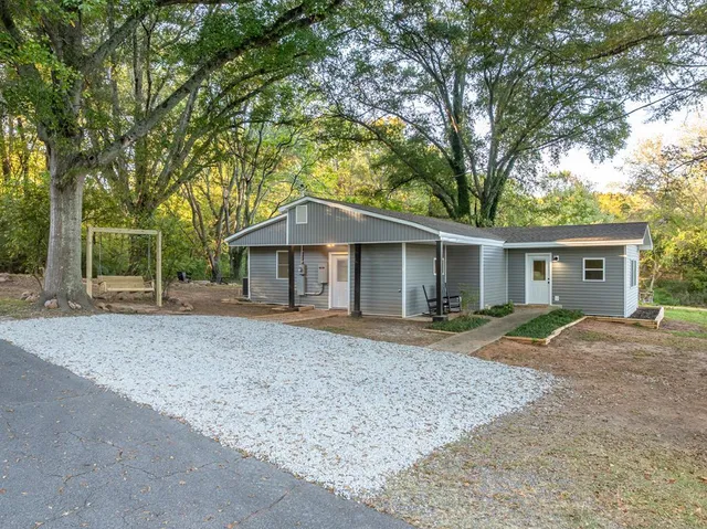 a view of a house with a yard and large tree
