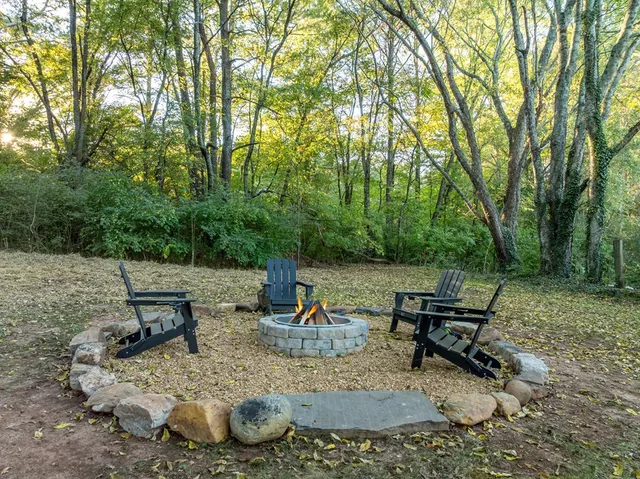 a view of a fire pit with chairs in a backyard
