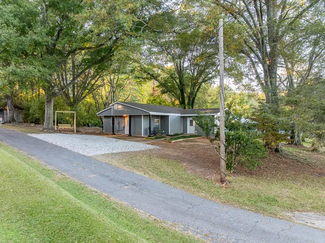 a view of a house with a yard and large trees