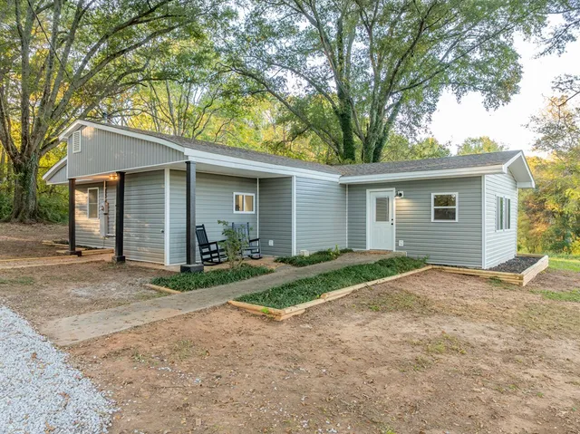 a view of a house with a yard and large tree
