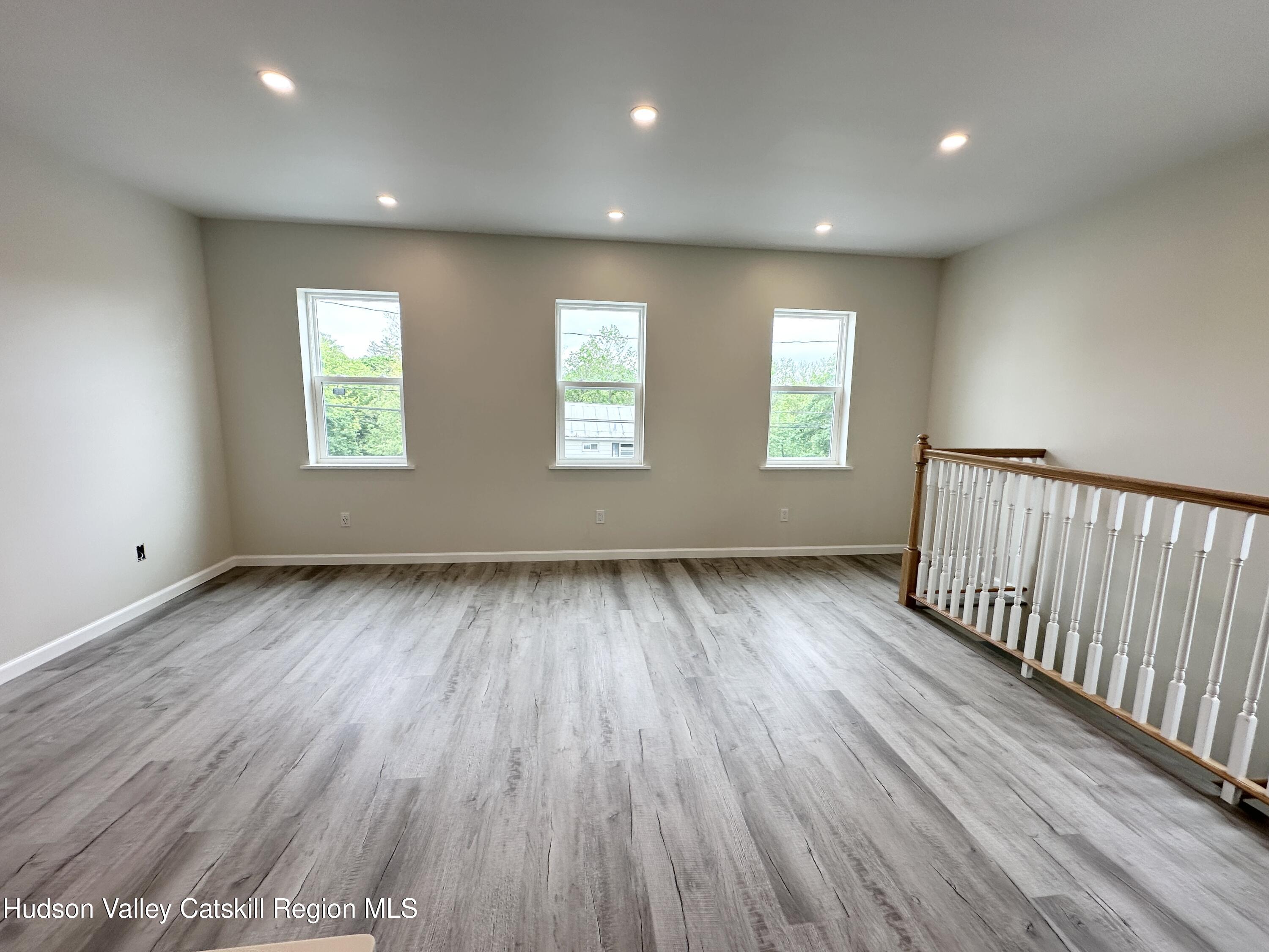 61 Thompson Street, Unit 4 Catskill, NY 12414 - Photo 2 of 7 an empty room with wooden floor and windows