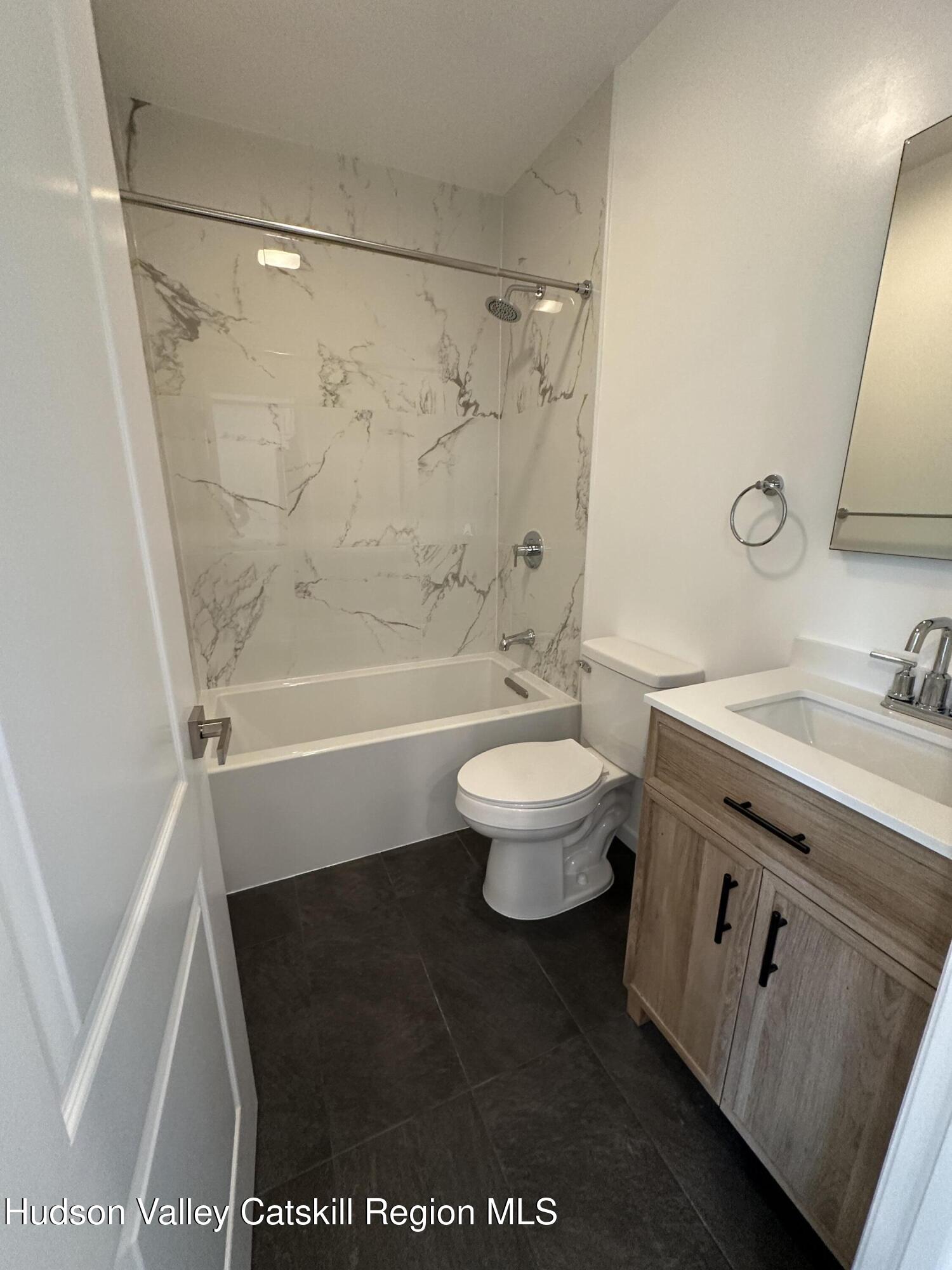 61 Thompson Street, Unit 4 Catskill, NY 12414 - Photo 4 of 7 a bathroom with a granite countertop sink toilet and shower