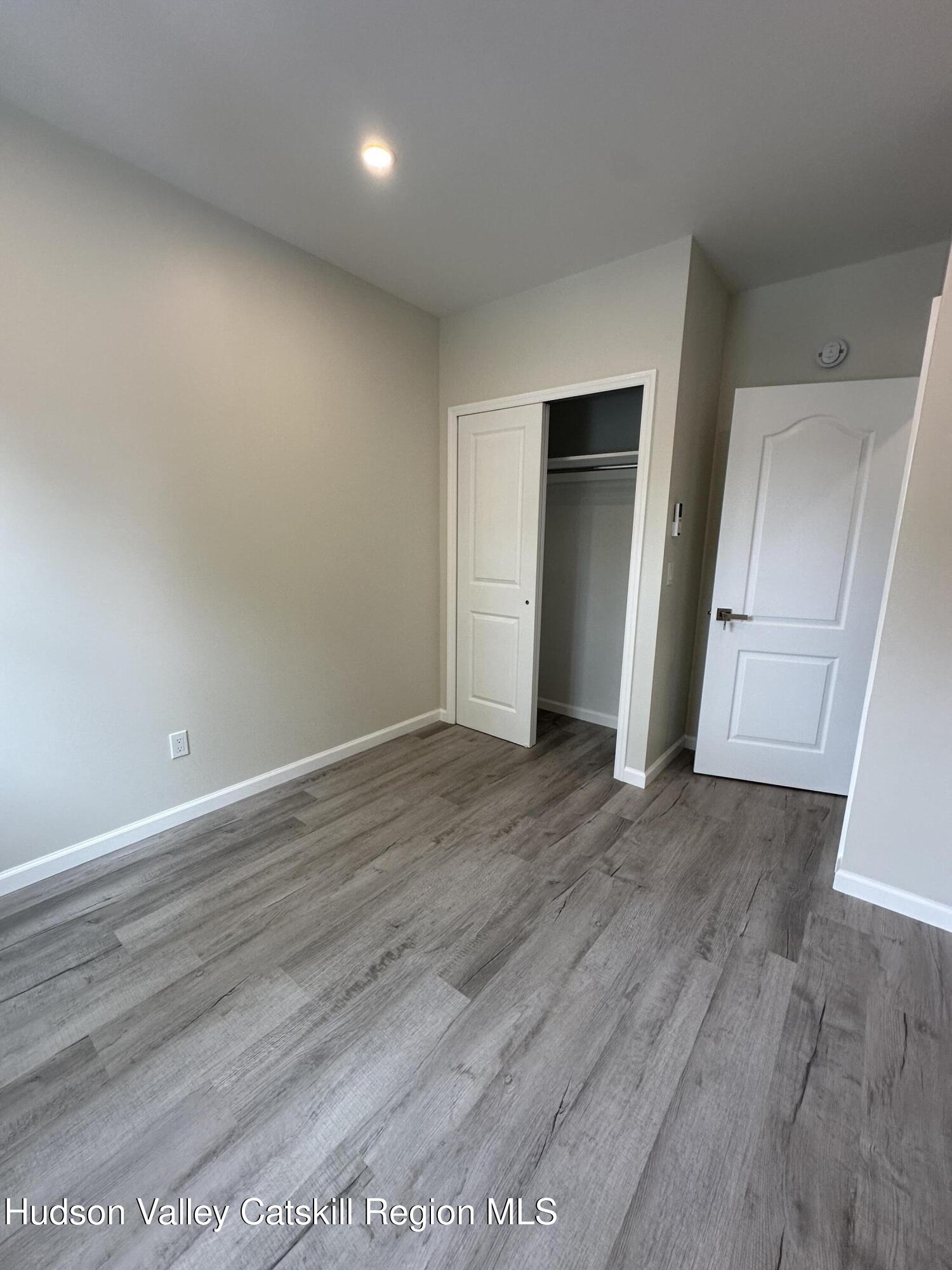 61 Thompson Street, Unit 4 Catskill, NY 12414 - Photo 5 of 7 an empty room with wooden floor and closet