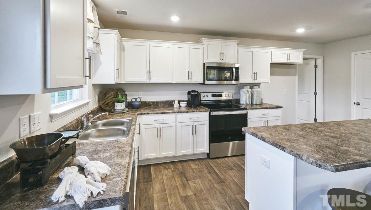 4032 Water Wheel Road Rocky Mount, NC 27803 - Photo 11 of 29 a kitchen with stainless steel appliances granite countertop a stove top oven a sink a refrigerator white cabinets and wooden floor