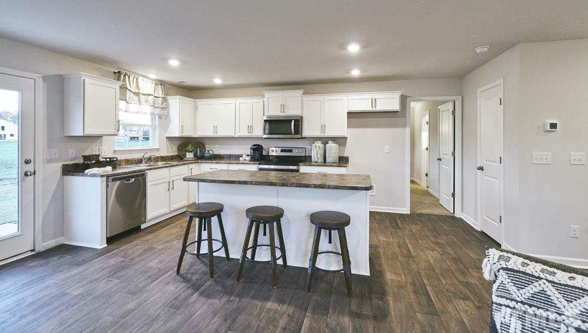 4032 Water Wheel Road Rocky Mount, NC 27803 - Photo 12 of 29 a kitchen with stainless steel appliances granite countertop a stove top oven a sink dishwasher a refrigerator and white cabinets with wooden floor