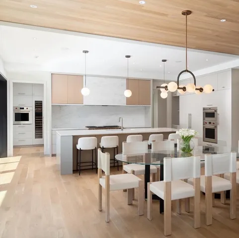 a living room with couches chairs and kitchen view with wooden floor
