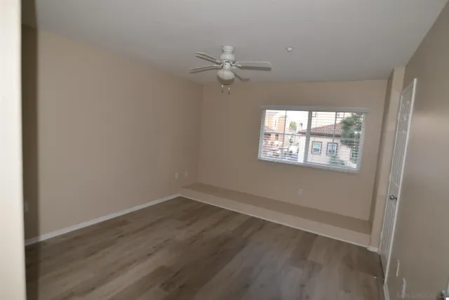 an empty room with wooden floor fan and windows