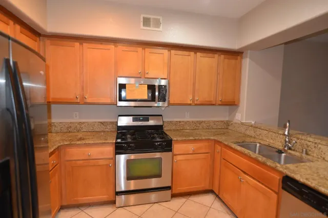 a kitchen with granite countertop a refrigerator stove and sink