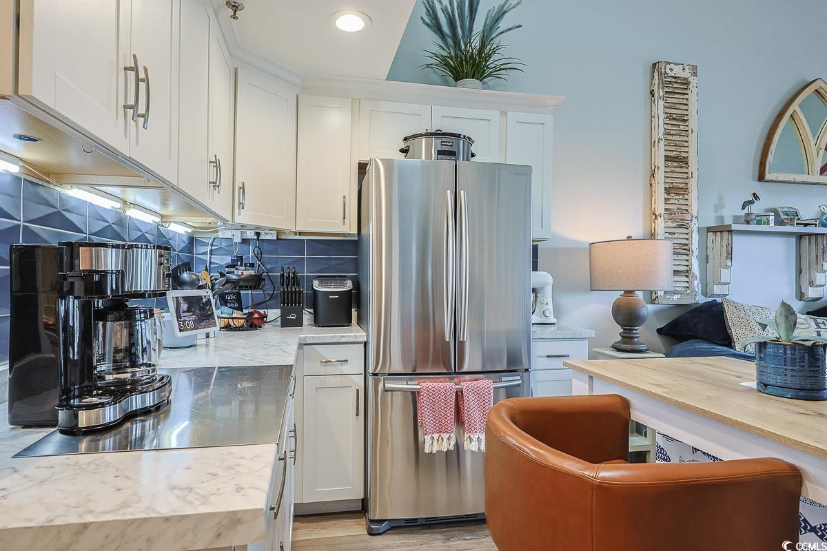 1100 Possum Trot Road, Unit G324 North Myrtle Beach, SC 29582 - Photo 11 of 28 Kitchen featuring freestanding refrigerator, white cabinetry, tasteful backsplash, and light wood finished floors