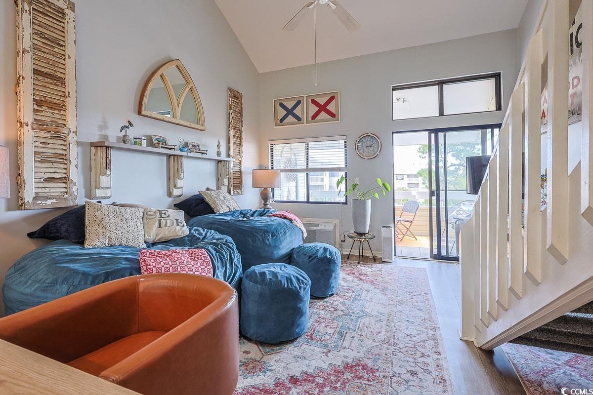 1100 Possum Trot Road, Unit G324 North Myrtle Beach, SC 29582 - Photo 4 of 28 Living area with high vaulted ceiling, wood finished floors, ceiling fan, and a wall unit AC