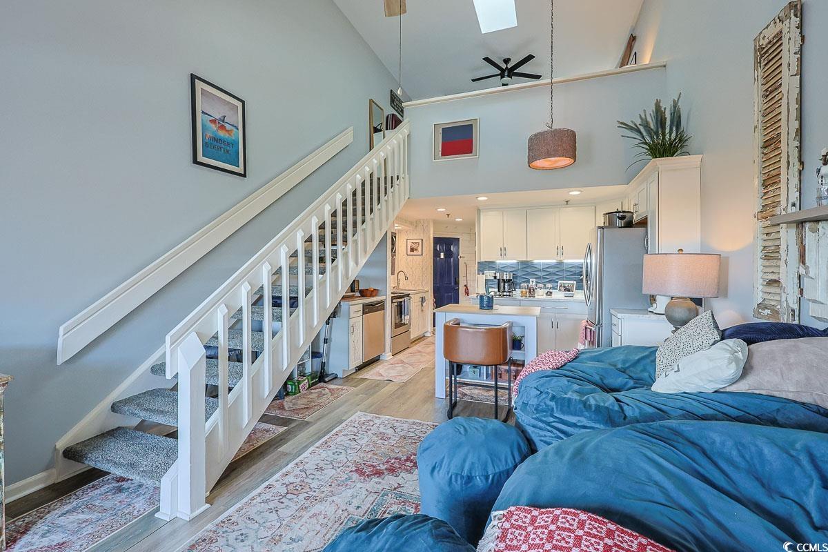 1100 Possum Trot Road, Unit G324 North Myrtle Beach, SC 29582 - Photo 5 of 28 Living room with stairs, light wood-type flooring, a ceiling fan, a towering ceiling, and a skylight