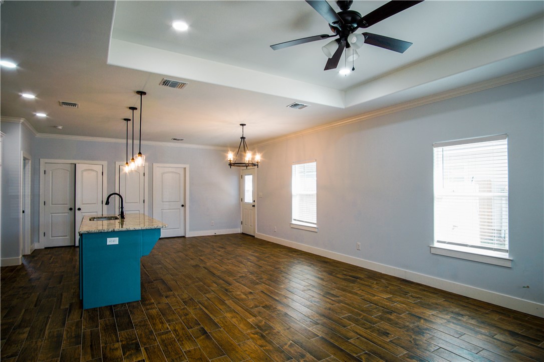 1614 Louis Street Bryan, TX 77803 - Photo 2 of 29 Kitchen with decorative light fixtures, an island with sink, wood tiled floors, a tray ceiling, and recessed lighting
